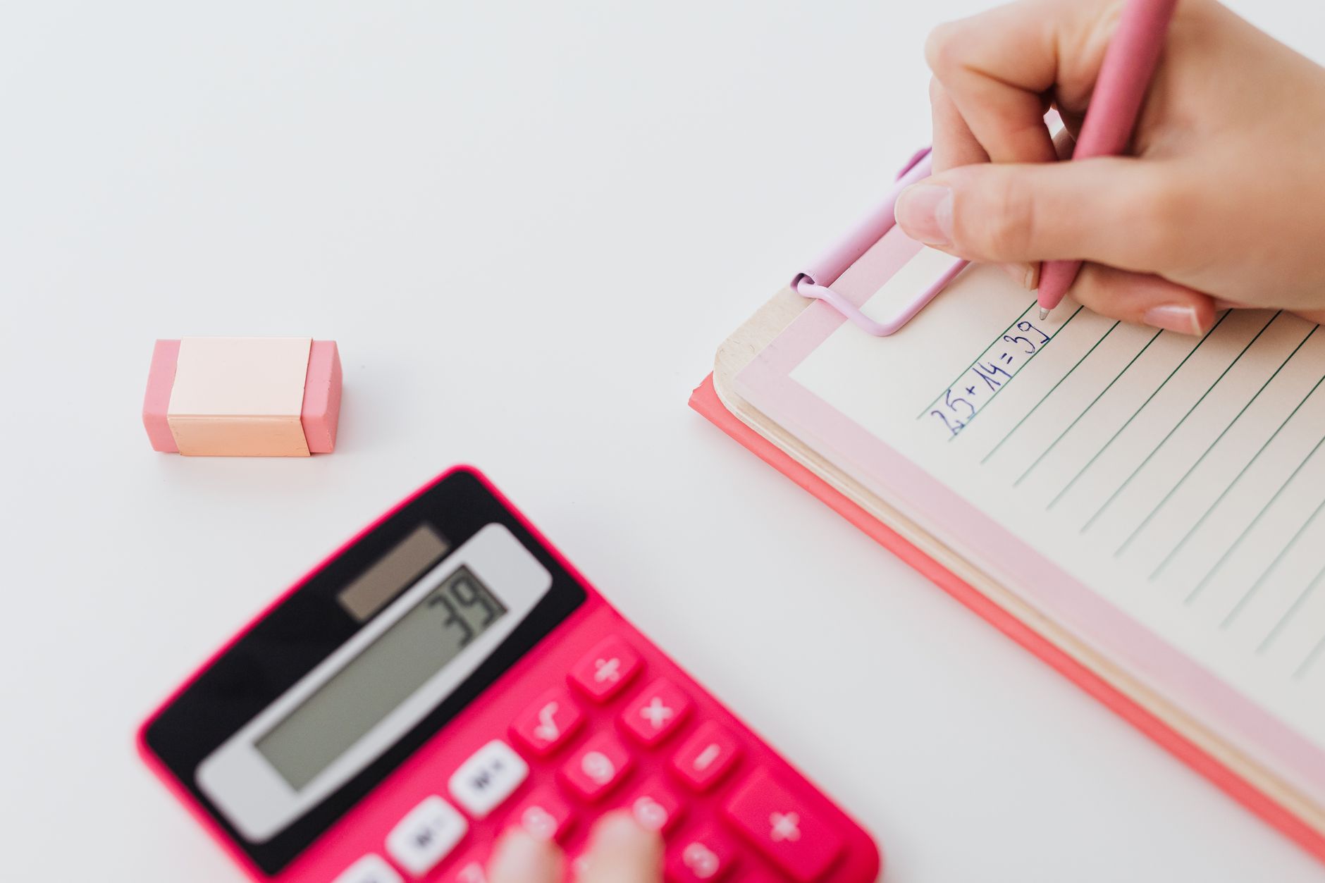 Gros plan sur des mains utilisant une calculatrice et écrivant des équations dans un carnet