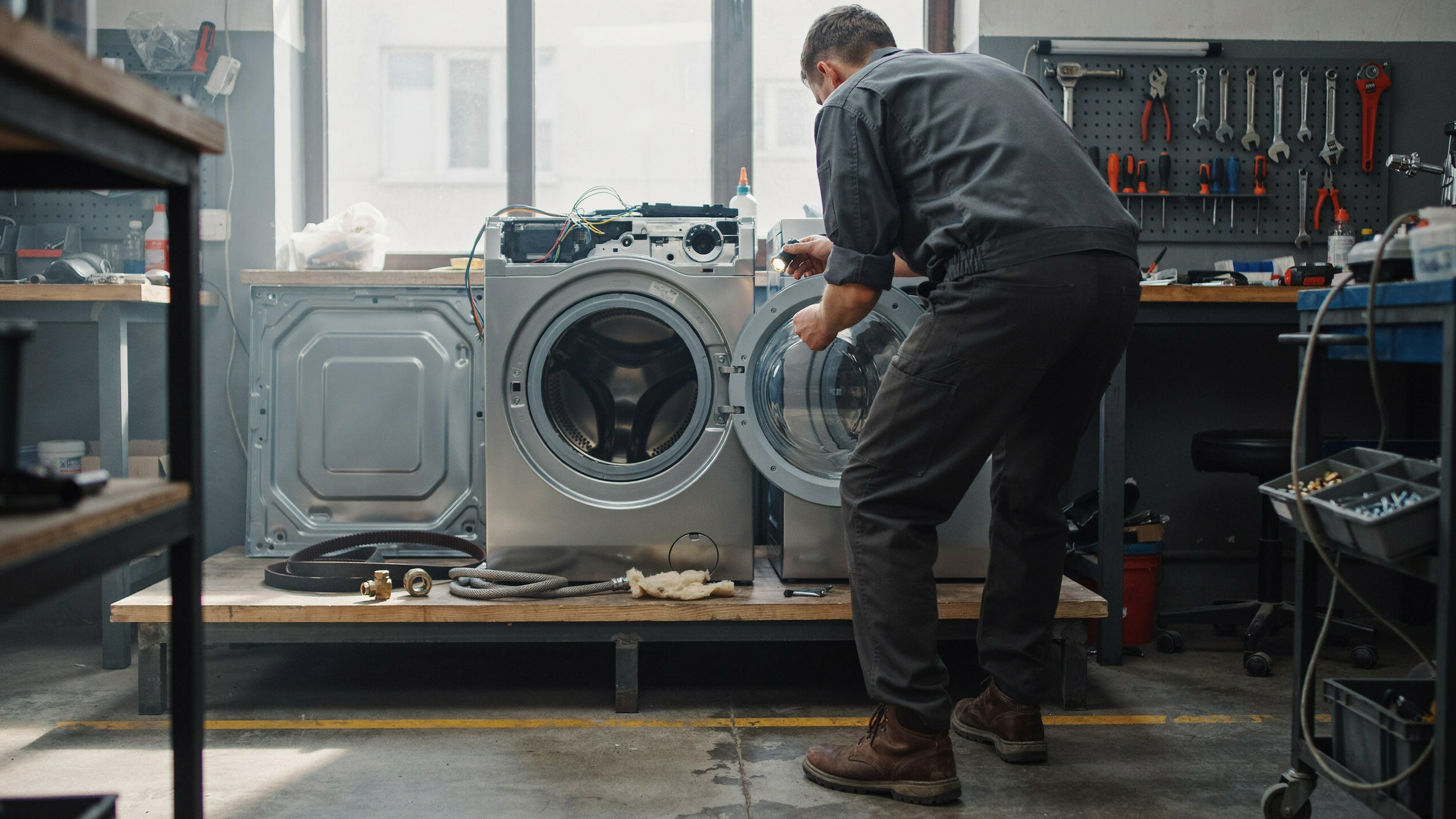 Un réparateur examine des pièces détachées de lave-linge dans un atelier