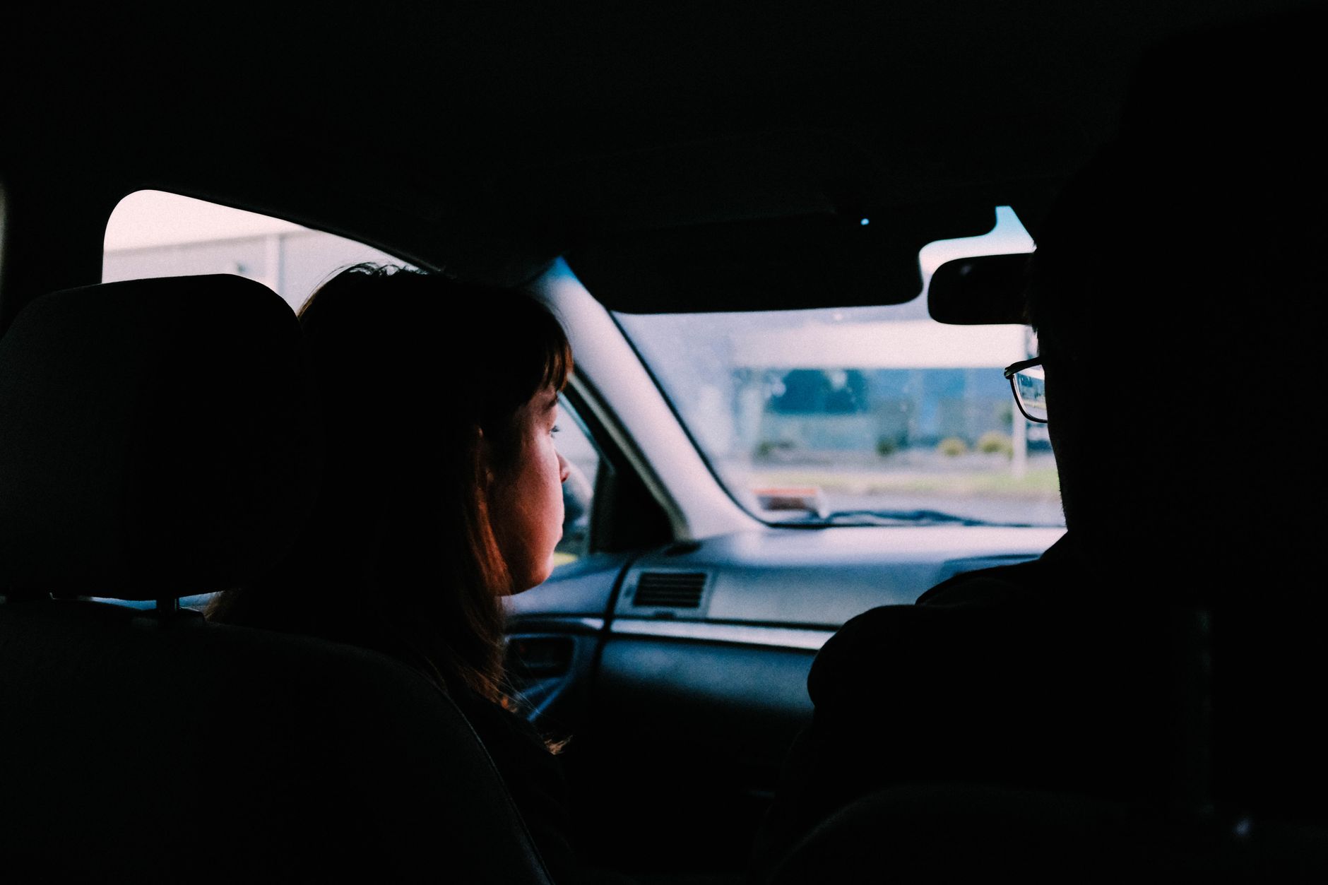 Silhouettes de deux passagers à l'avant d'une voiture, à contre-jour