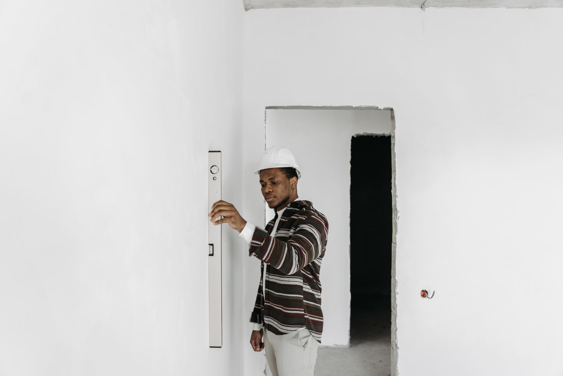 Un architecte portant un casque de sécurité vérifie l'alignement des murs dans un projet de rénovation.