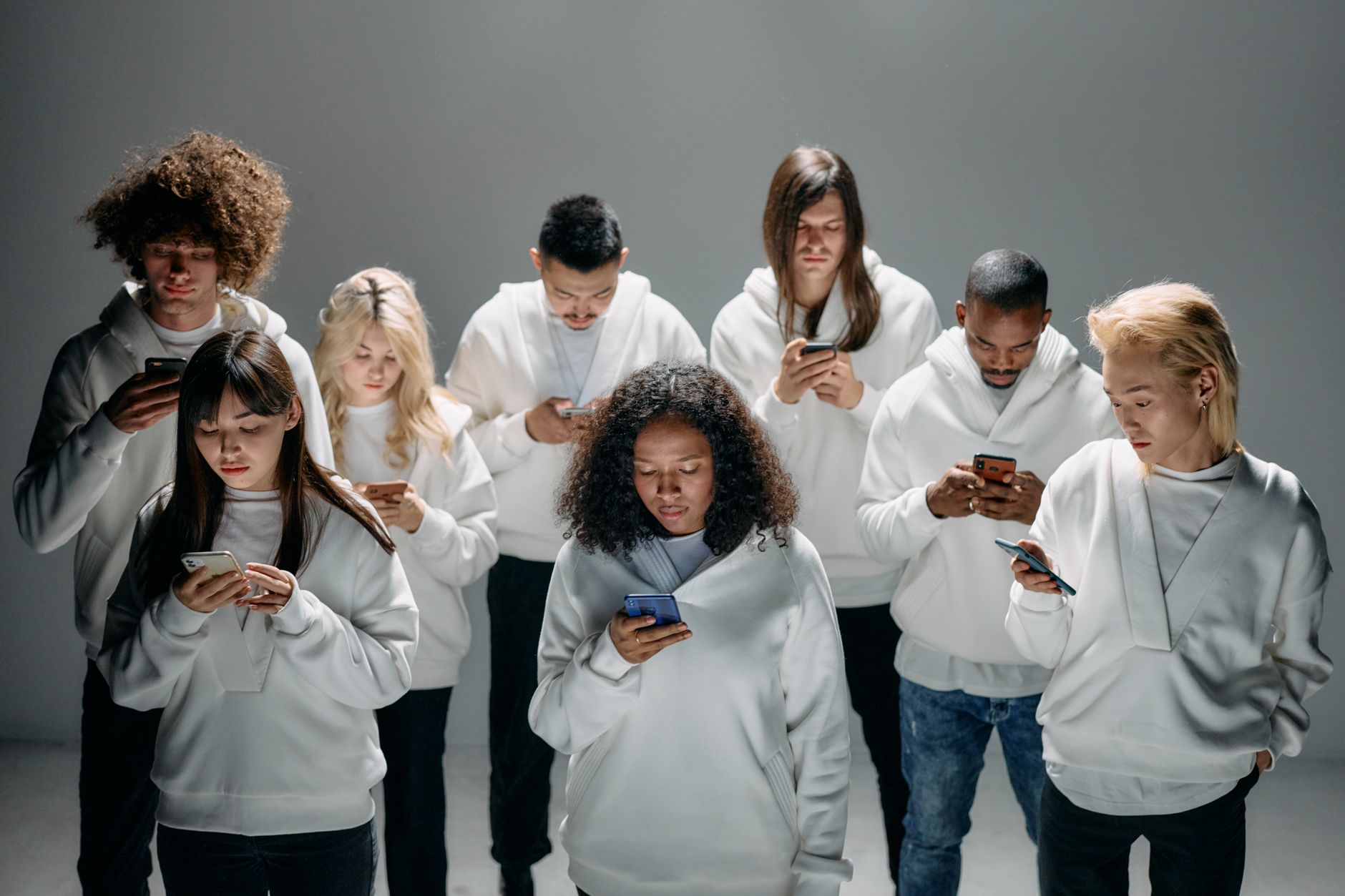 Un groupe divers de personnes en hoodies blancs engagées avec des smartphones
