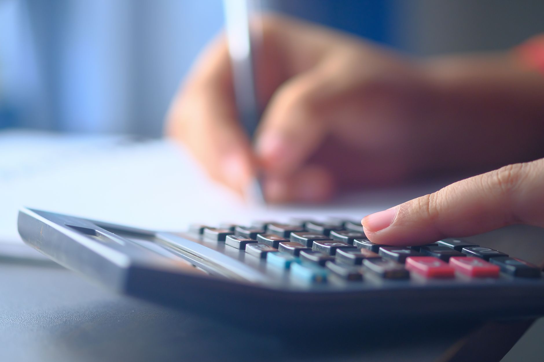 Une image en gros plan de mains utilisant une calculatrice et écrivant