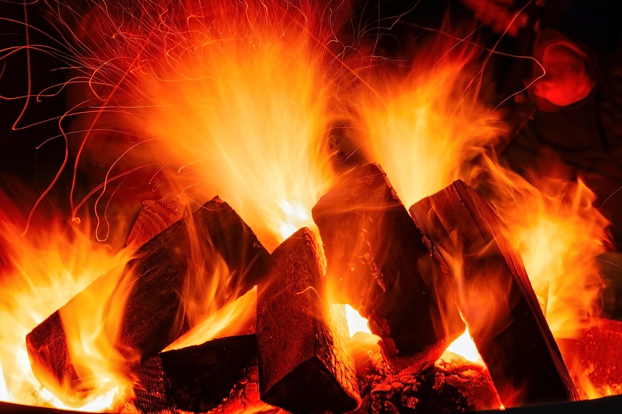 Bûches en flammes avec des étincelles dans un foyer, vue rapprochée.