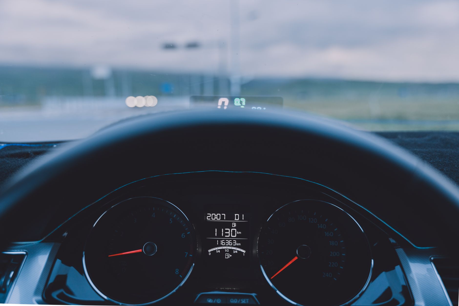 Vue depuis le siège conducteur sur le volant et le tableau de bord d'une voiture roulant sur une route.